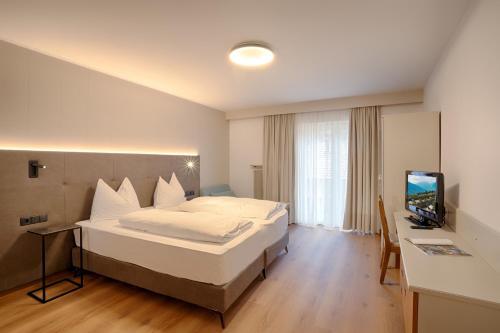 a bedroom with a bed and a desk and a television at Hotel Lamm in Naturno