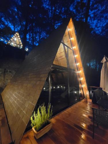 a pyramid shaped house with a wooden deck at night at Arce Cabañas Mazamitla in Mazamitla