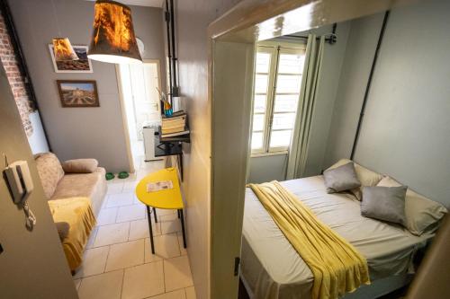 a small room with a bed and a yellow chair at Apartamento central com pátio, 1 quadra do calçadão in Santa Maria