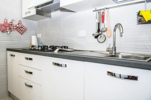 a kitchen with white cabinets and a sink at Domus Etruria in Civitavecchia