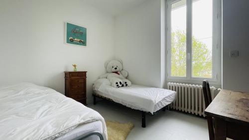 - un ours en peluche assis sur un lit dans une chambre dans l'établissement Maison de vacances calme pour 4-6 personnes, à Saint-Palais-sur-Mer