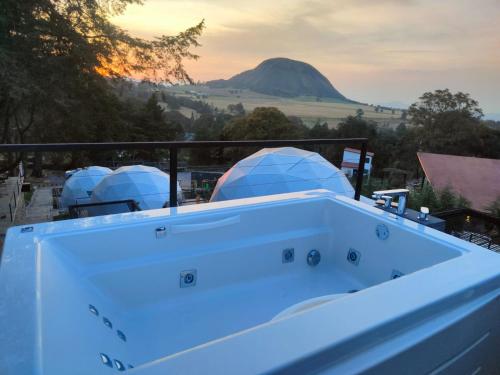 a hot tub with a mountain in the background at Hotel Glamping & Restaurant Fuerza Ancestral in Tlalmanalco de Velázquez