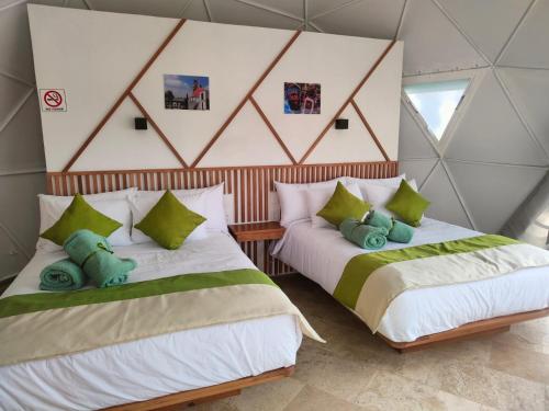 two beds in a room with green and white at Hotel Glamping & Restaurant Fuerza Ancestral in Tlalmanalco de Velázquez