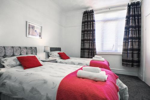 a bedroom with two beds with red and white sheets at Beachmount Holiday Apartments in Colwyn Bay