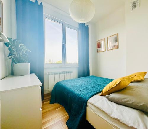 a bedroom with blue walls and a bed and a window at Green&Comfy Apartment Żoliborz in Warsaw