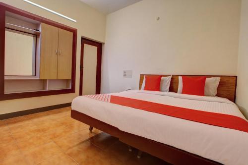 1 dormitorio con 1 cama grande con almohadas rojas en OYO Hotel Radhakrishna, en Madurai