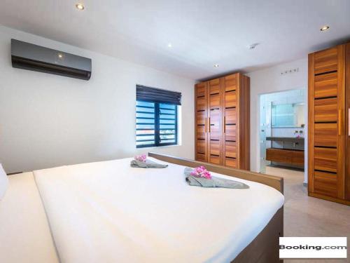 a bedroom with a large white bed with wooden cabinets at Villa met zeezicht & infinitypool Jan Thiel Curacao in Jan Thiel