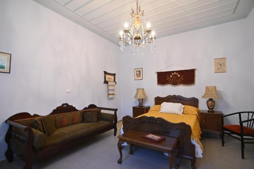 a bedroom with a bed and a couch and a chandelier at Phaos Chios in Vrontados