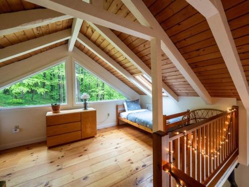 een slaapkamer op zolder met een bed en een groot raam bij Berkshire Vacation Rentals: Loft Style Cabin In West Stockbridge Book Now in West Stockbridge