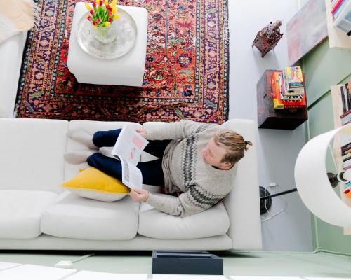 Una donna sdraiata su un divano a leggere un libro di Villa Loimu ad Antskog