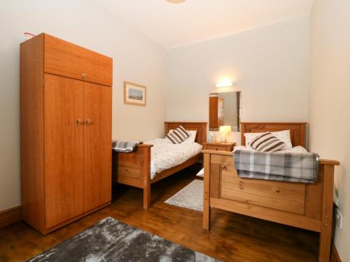 a bedroom with two beds and a wooden cabinet at Ty Gwenyn in Holyhead