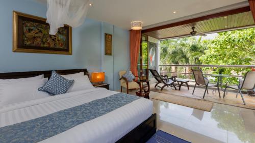 a bedroom with a bed and a balcony at Talay Naiharn Hotel in Rawai Beach