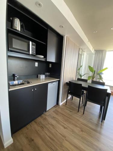 a kitchen and dining room with a table and a microwave at Hotel Ciudadano Suites in Montevideo