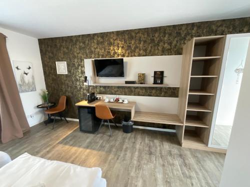Zimmer mit einem Schreibtisch und einem TV an der Wand in der Unterkunft Gästehaus Estenfeld bei Würzburg 24 h in Estenfeld