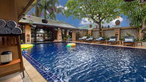 a large swimming pool with chairs and a resort at Talay Naiharn Hotel in Rawai Beach