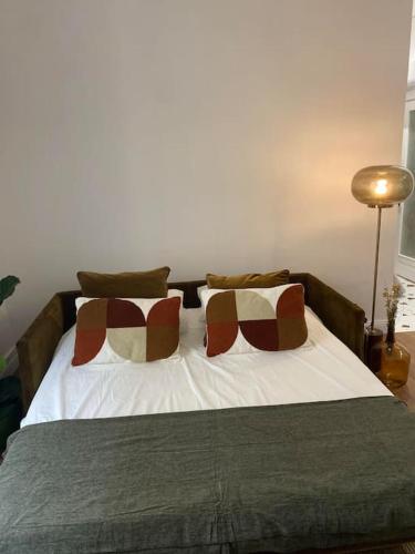 une chambre avec un lit avec deux oreillers dessus dans l'établissement La Halte des Arènes de Nîmes Emeraude, Havre de paix en ville, à Nîmes