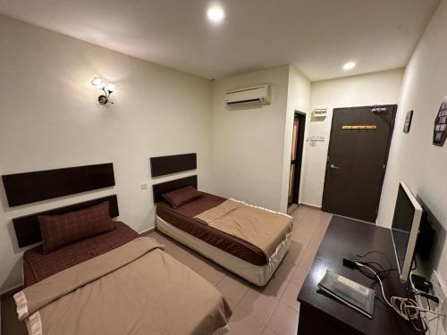 1 Schlafzimmer mit 2 Betten und einem Schreibtisch mit einem Computer in der Unterkunft Ezzy In Hotel in Seri Manjung