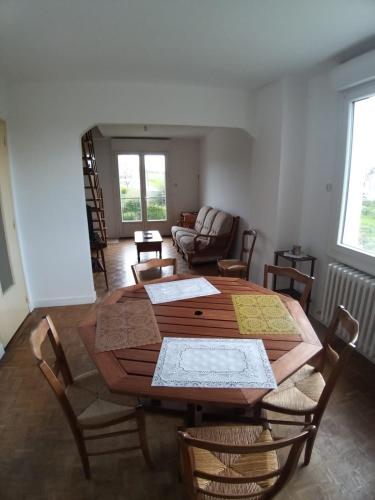 un salon avec une table et des chaises en bois dans l'établissement Saint Brieuc sortie ville Logement dans maison année 1970 disposant de 5 chambres 6 personnes adultes ou enfants, à Saint-Brieuc