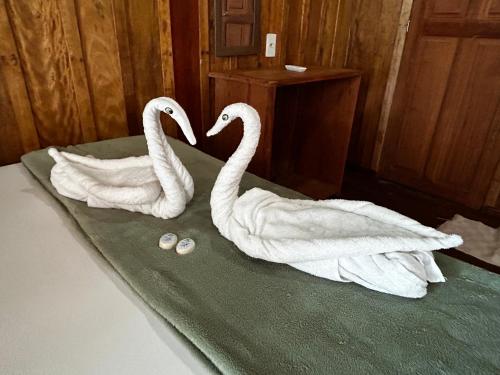 two white swans sitting on top of a bed at Vista do Lago Jungle Lodge in Cajual