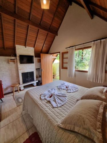 a bedroom with a large bed and a fireplace at Pousada Vilas di Espanha in Monte Verde
