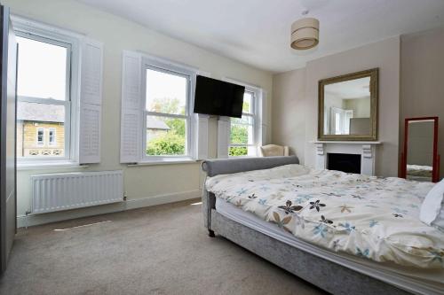 1 dormitorio con cama, espejo y ventanas en orwell villa elegant period 5 bed close to town sleeps 15, en Cheltenham