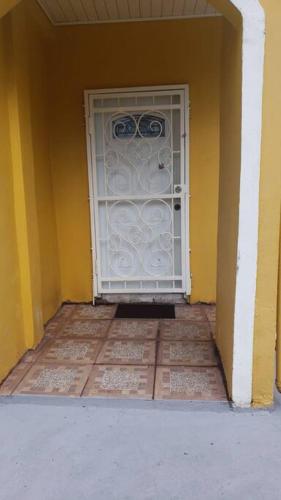 a white door in a yellow wall with a floor at Lovely 2 bedroom vacation home with free parking. in Georgetown