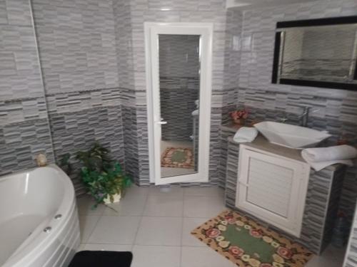 ein Badezimmer mit einer Badewanne, einem Waschbecken und einem WC in der Unterkunft magnifique villa avec piscine in Dawwār al Frinine