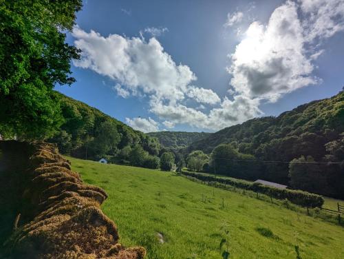 un campo de césped verde con montañas en el fondo en Voulwill Cottage en Lynton