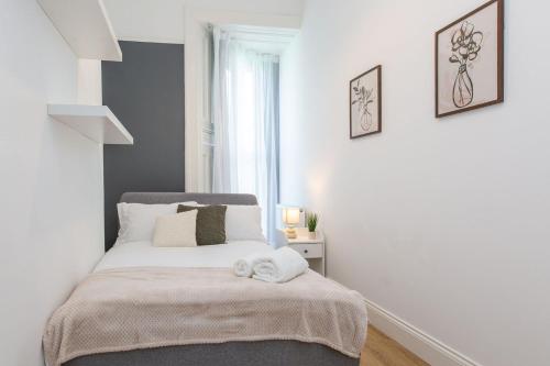 Un dormitorio blanco con una cama con una toalla. en Free Parking | Free Wifi | Smart TV en Sketty