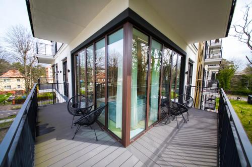 una casa con puertas de cristal y sillas en el balcón en Wyspa Uznam Sea Side Garden Resort Promenada, en Świnoujście