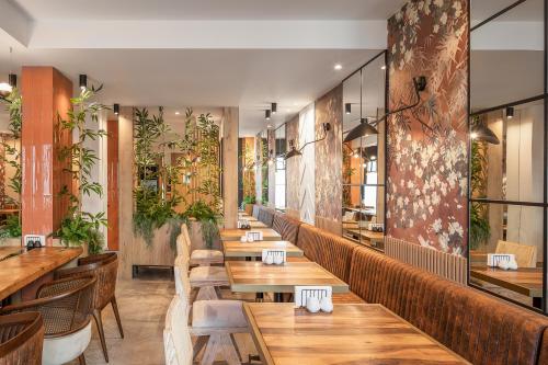 a restaurant with wooden tables and chairs and plants at Hotel Branco Timisoara in Timişoara