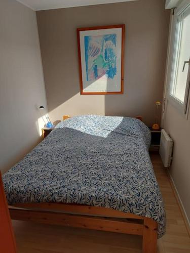 een bed in een slaapkamer met een foto aan de muur bij Appartement Hardelot plage in Neufchâtel-Hardelot
