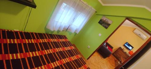 um quarto verde com uma cama e um espelho em Čardak em Kneževac