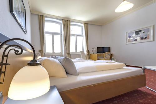 a bedroom with a large white bed with a lamp at Hotel Barbarossa in Reichshof 