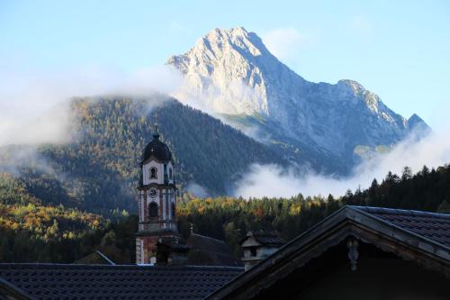 un edificio con una torre de reloj frente a una montaña en Ferienwohnung Karwendelblick, en Mittenwald