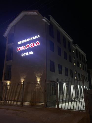 een bord aan de zijkant van een gebouw 's nachts bij Нарэл in Bisjkek