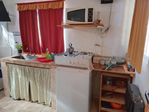 a small kitchen with a stove and a microwave at DORMI-con HIDROMASAJE- POSADA RUTA 22 totalmente EQUIPADO in Plottier