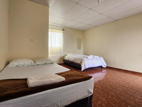 Cette chambre comprend 2 lits et une fenêtre. dans l'établissement Hostal Carolinas, à Juayúa