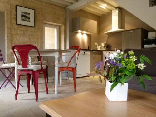 une cuisine avec des chaises rouges et une table avec un vase de fleurs dans l'établissement Clos de la Valette, à Fontaine-Henry