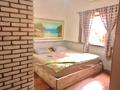 a bed in a room with a brick wall at Suíte Explorer in Praia Grande