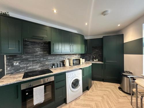 a kitchen with green cabinets and a washer and dryer at Kings Gate House DH ApartHotels in Peterborough
