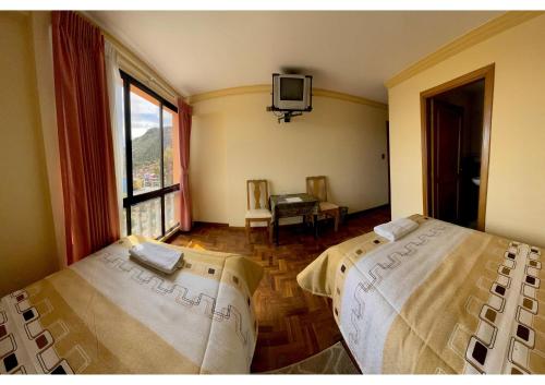 a bedroom with two beds and a tv on the wall at HOTEL WENDY MAR in Copacabana