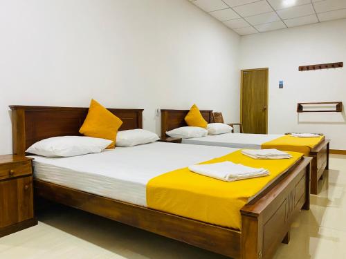 two beds in a room with yellow pillows at Carmel Hill Resort in Ambagamuwa