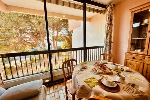 une salle à manger avec une table et un balcon dans l'établissement Triangle de la Baronnie Appartement 1 chambre proche de la Mer, au Grau-du-Roi