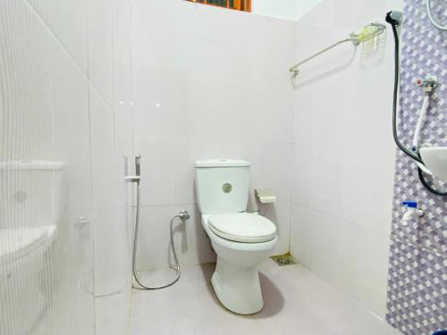 a white bathroom with a toilet and a shower at Carmel Hill Resort in Ambagamuwa