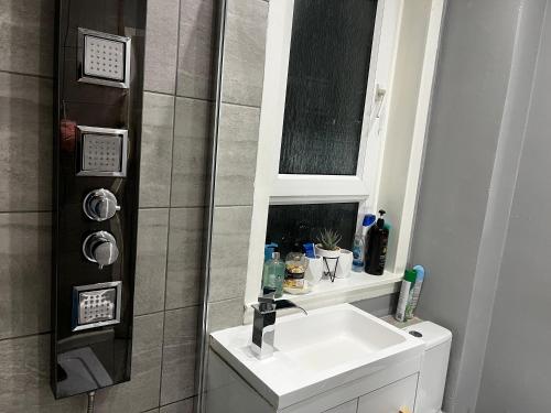 uma casa de banho com um lavatório e um chuveiro com um espelho. em Mini hotel with home facilities in Hamilton West em High Blantyre