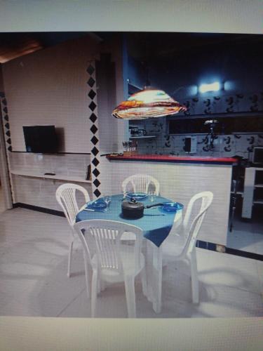 a dining room table with white chairs and a blue table at Bangalô Cristal in Itaparica Town