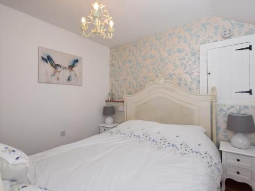 een slaapkamer met een wit bed met blauw bloemenbehang bij 1 bed property in Banham 53952 in Banham