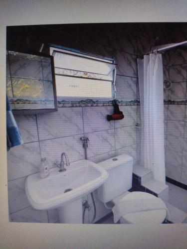 La salle de bains blanche est pourvue d'un lavabo et de toilettes. dans l'établissement Bangalô Cristal, à Itaparica Town