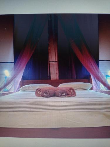 a bed with two rolled up towels on it at Bangalô Cristal in Itaparica Town